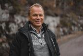 En mann står på grusvei. Frister for å skifte dekk